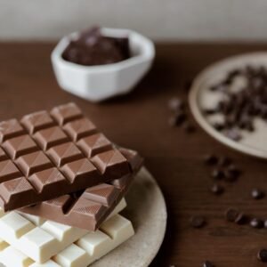 High angle of delicious bars of chocolate on plate on wooden table with scattered chocolate chips